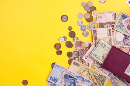 Passport with paper money and coins. Flatlay of vacation on yellow background.