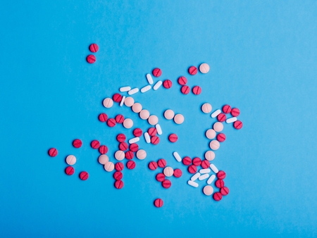 Multicolored medical pills and drugs on a blue background