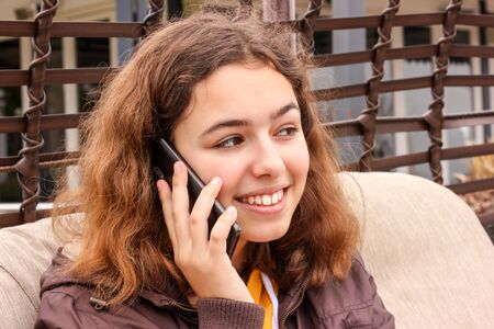 Cute cheerful teenager girl talking by the phone and smilingの写真素材