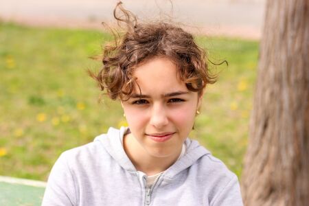 Portrait of a calm curly teenager girl outside at the parkの写真素材