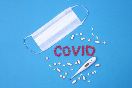 Virus protection - medical mask, thermometer and medicines on blue background