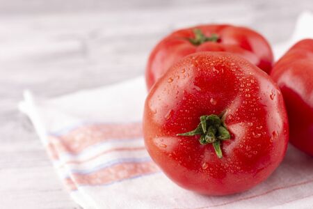 Large pink tomatoes with droplets of water. Fresh ripe vegetables on a wooden tableの写真素材