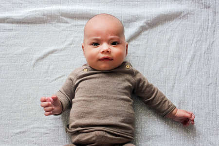 Portrait of cute baby close-up. Sweet little infant looks to camera. Bald baby with brown eyes and long lashesの写真素材