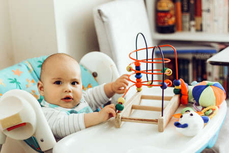 Baby boy playing toys in a high chair at homeの写真素材