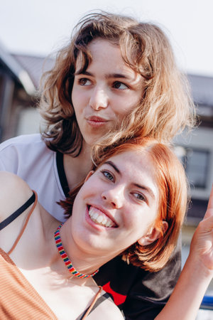 Two teenager girls together. Girl friendship. Red hair and curly hairの写真素材