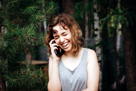 Beautiful teenager girl talking by phone at the forest.の写真素材