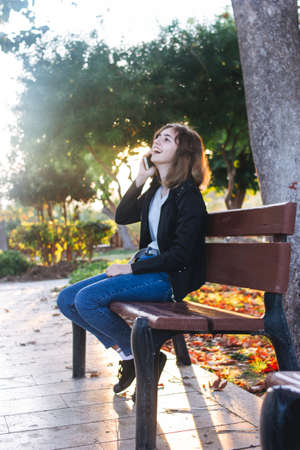 Teenager girl taking by phone on the bench in the parkの写真素材
