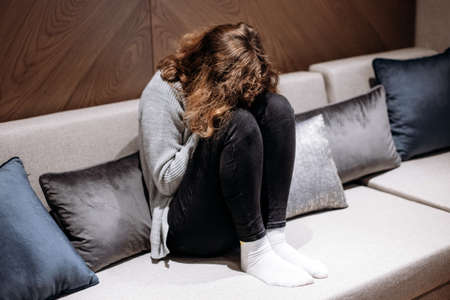 Teenager girl crying on the couch. Puberty and depression