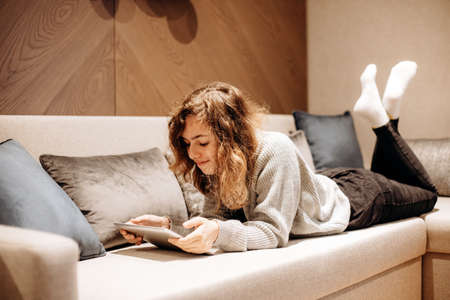 Teenager girl reading book on couch at home