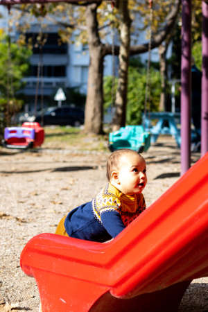 Cute baby boy having fun at outdoors playground. Toddler on plastic slideの写真素材