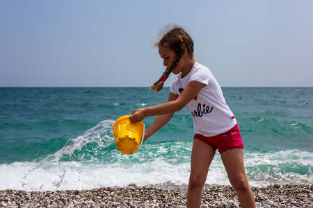Little girl playing on the beach near by blue seaの写真素材
