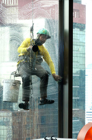 A view from inside the building showing workers rappelling and cleaning glass outside the building.の写真素材