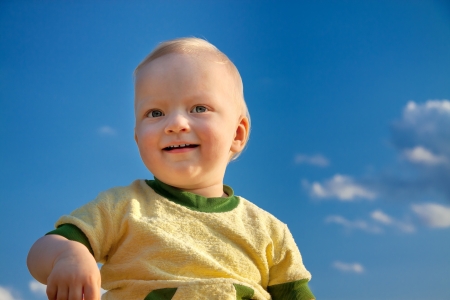 the beautiful small child smiling against the blue skyの写真素材
