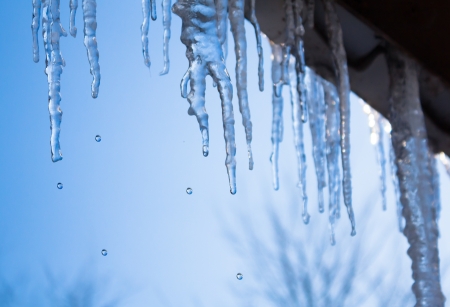 beautiful icicles glint in the sun against the blue skyの写真素材