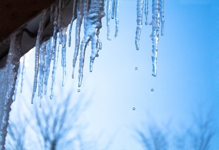 beautiful icicles glint in the sun against the blue skyの写真素材