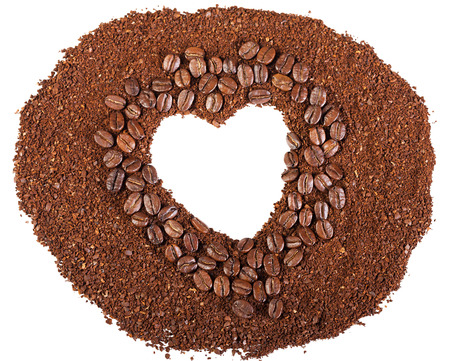 background from coffee beans in the frame of heart isolated on the whiteの写真素材