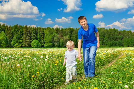 two brothers, small child and teenager  plays on a summer meadow の写真素材