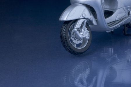 Toy vespa scooter hovering over a blue reflecting surface
