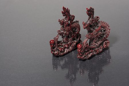 two dragon statue racing on a gray reflective surfaceの写真素材