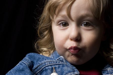 Portrait of a two year old boy wearing a jean jacket making a kissing face