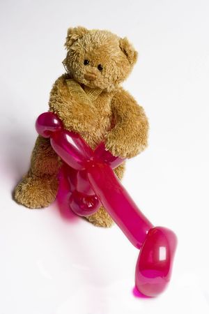 teddy bear sitting on a pink balloon bikeの写真素材