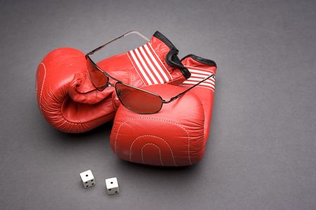 Men's sunglasses place on top of boxing gloves with a pair of dice rolled on snake eyesの写真素材