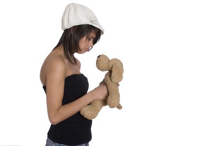 Teenage girl wearing a black tube top, knitted hat and jeans with holes holding a brown stuff dog plush toy with sad expressionの写真素材