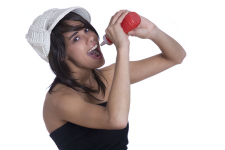 Teenage girl wearing a black tube top, knitted hat and jeans with holes squeezing ketchup in her mouth from a red bottleの写真素材