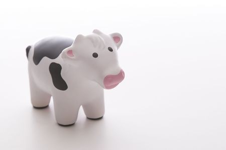 small black and white toy cow against white backgroundの写真素材
