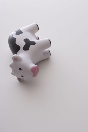 small black and white toy cow against white background tipped on it's sideの写真素材