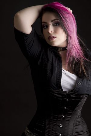 Goth girl with pink hair and body piercing holding her black and pink hairの写真素材