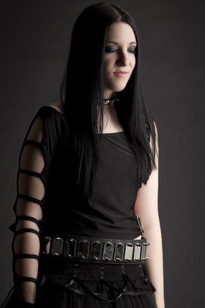 teen girl with black hair and goth style wearing a black tutu, her eye are close and she seems to be smiling at a funny thoughtの写真素材