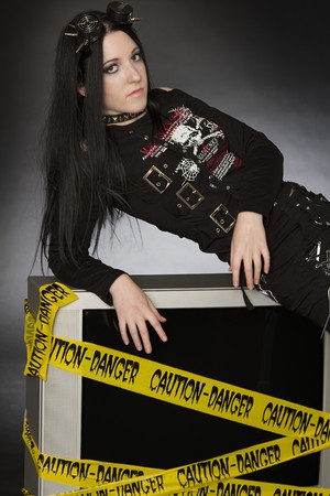 Teenage girl in goth style with spiked goggles on her head laying on a television