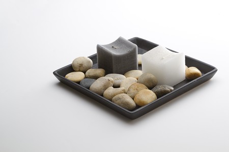 Dark grey and white candle in a plate with rounded rocksの写真素材