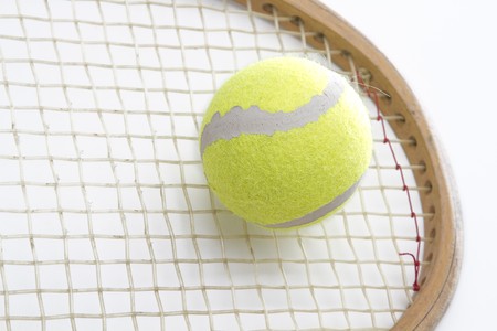Close-up on the head of a vintage wood tennis racket hitting a yellow ballの写真素材