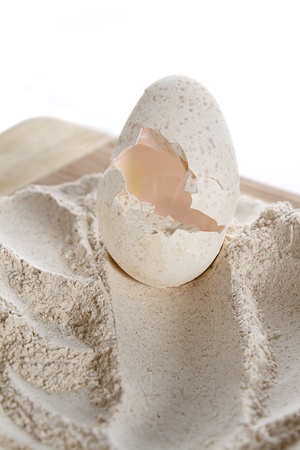 cracked turkey egg sitting on top of a mount of whole wheat flour