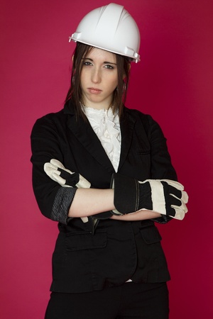 Young business woman wearing a business suit and construction clothing with angry expression against pink backgroundの写真素材