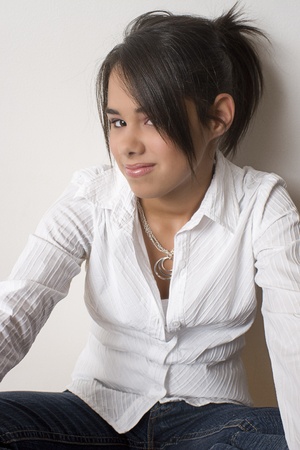Young teen girl sitting cross legged hidding behind her hairの写真素材