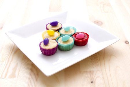 small cupcake in multicolored paper cup decorated by a color matching candyの写真素材