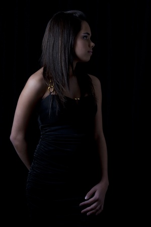 Teen girl wearing a little black dress against a black backgroundの写真素材