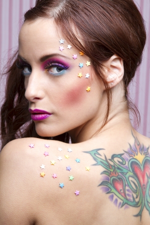 Young woman with colorful makeup and star candy glued to her face and her backの写真素材