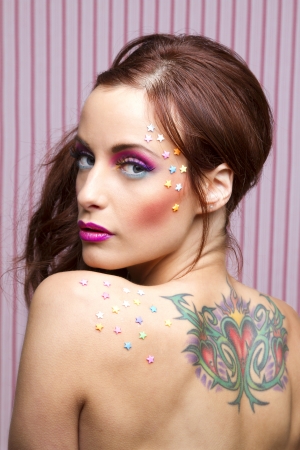Young woman with colorful makeup and star candy glued to her face and her backの写真素材