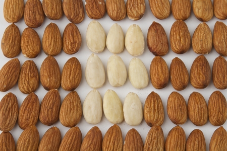 almond put in a row with group of peeled almond in the middleの写真素材