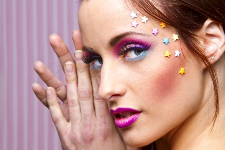 Young woman with colorful makeup and star candy glued to her faceの写真素材