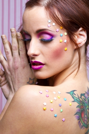 Young woman with colorful makeup and star candy glued to her face and backの写真素材