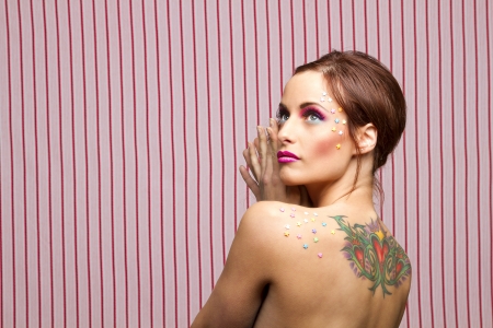 Young woman with colorful makeup and star candy glued to her face and back, looking upの写真素材