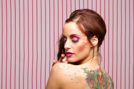 Young woman with colorful makeup and star candy glued to her face and back with her eyes closeの写真素材