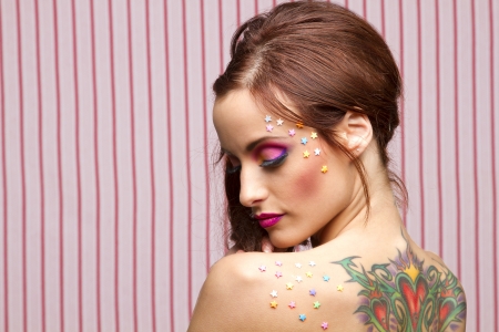Young woman with colorful makeup and star candy glued to her face and back with her eyes closeの写真素材