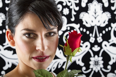 young woman in front of a black and white textured, holding a roseの写真素材