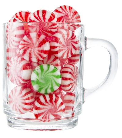 hard red and white candy mints with a green one in the middke in a transparent cupの写真素材